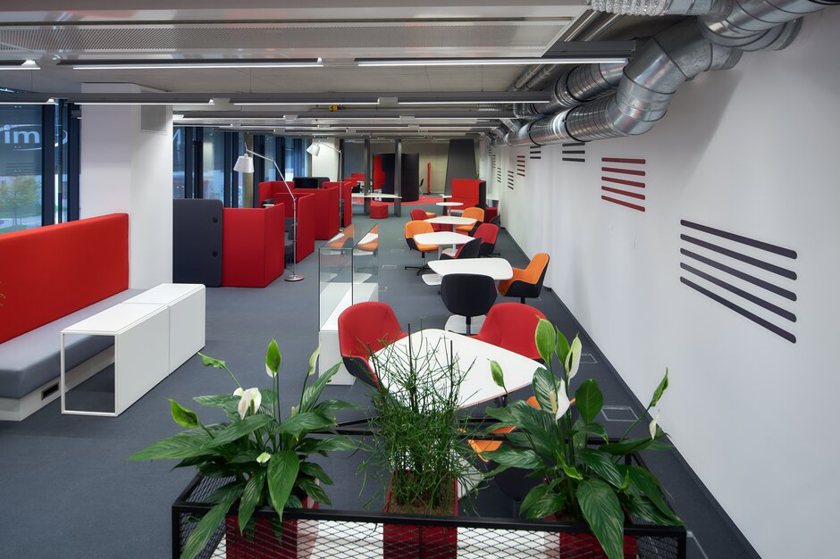 Overview of a lounge area with red and orange furniture. | © raumpixel.at