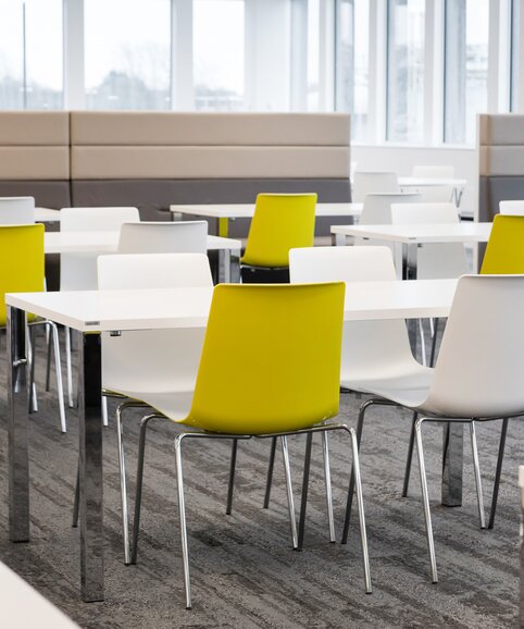 Ford | © Ford Motor Company Limited Canteen with white tables and yellow and white chairs. | © Ford Motor Company Limited