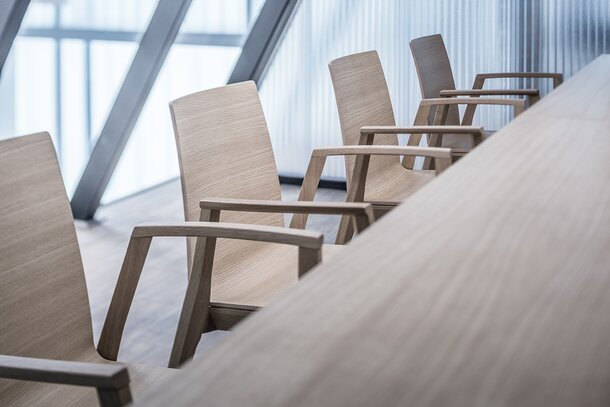 Detailed view of wooden chairs at a wooden table.