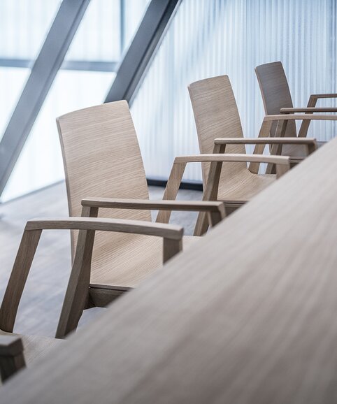 Detailed view of wooden chairs at a wooden table.