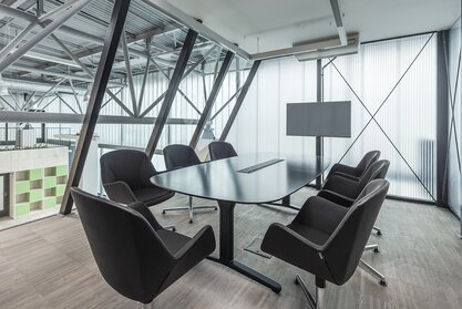 Impact HUB Dunkler Konferenztisch mit Konferenzstühlen in verglastem Büro.