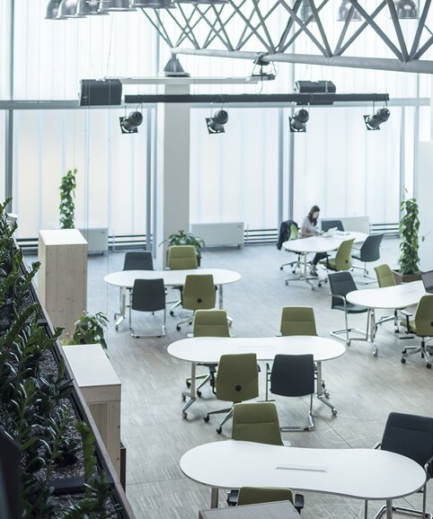 Work space with green and blue swivel chairs at white tables.