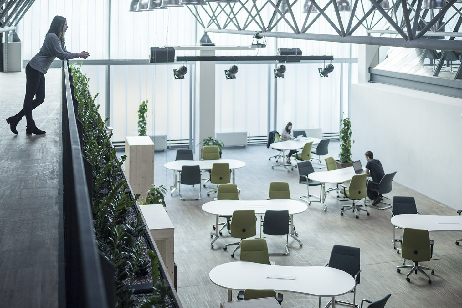 Work space with green and blue swivel chairs at white tables.