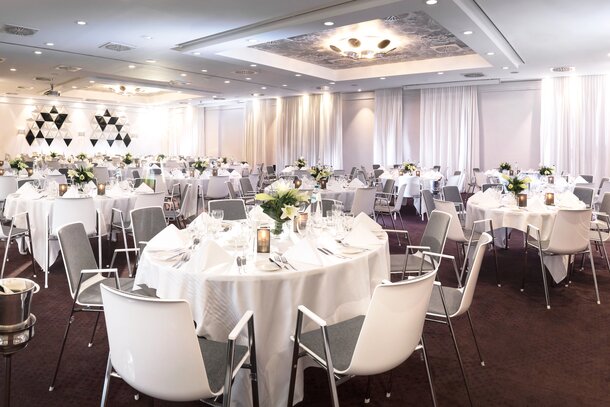 Salle à manger décorée avec tables rondes et chaises blanches. | © studio-bergoend.com