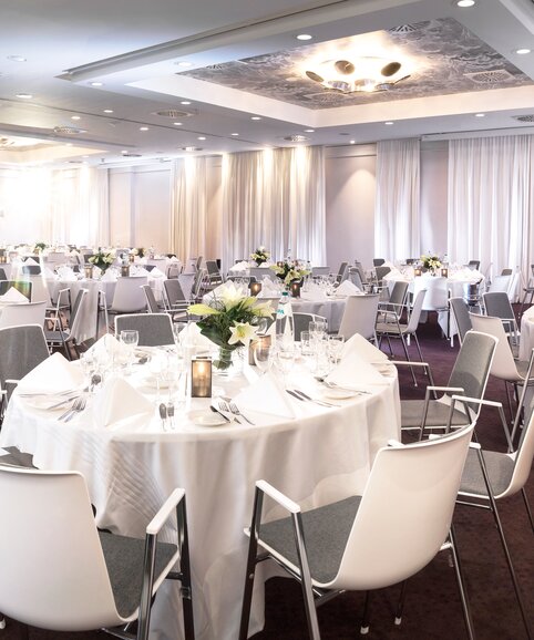 Salle à manger décorée avec tables rondes et chaises blanches. | © studio-bergoend.com