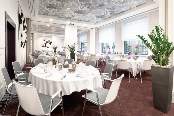 Salle à manger décorée avec tables rondes et chaises blanches.