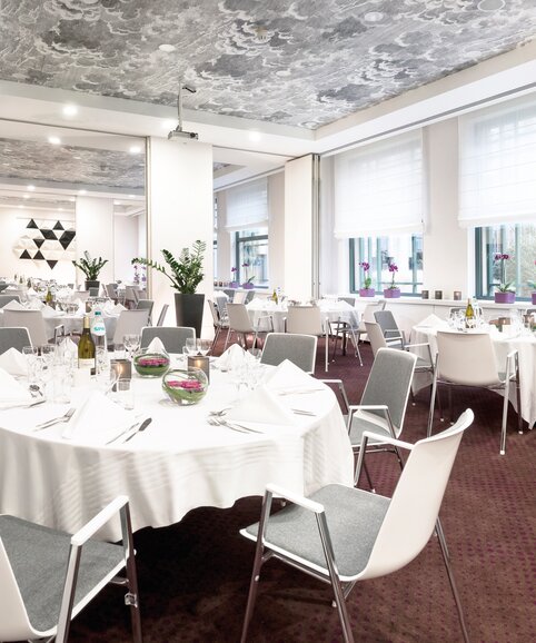 Salle à manger décorée avec tables rondes et chaises blanches.
