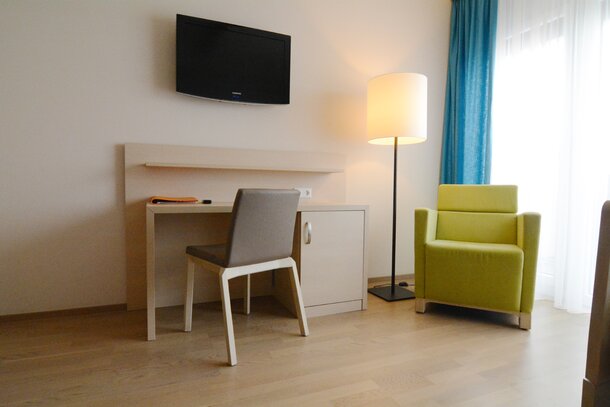 Room with a brown chair and green lounge seating.