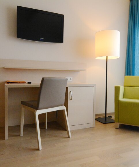 Room with a brown chair and green lounge seating.