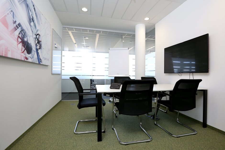 Salle de conférence avec fauteuils de luge foncés et plancher vert.