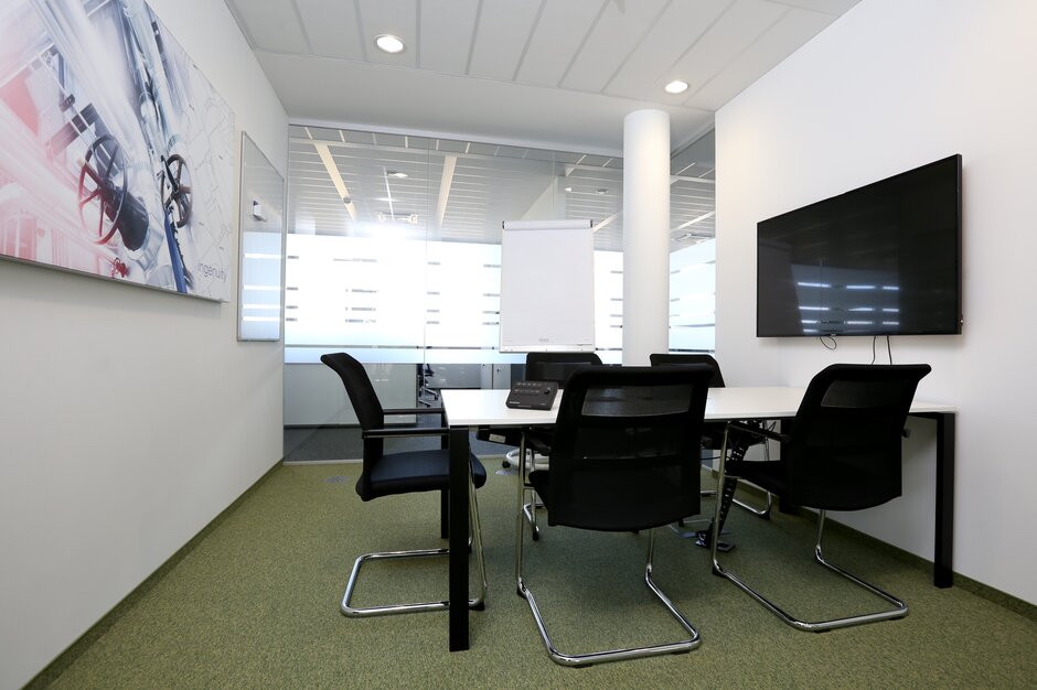 TÜV Austria Salle de conférence avec fauteuils de luge foncés et plancher vert.