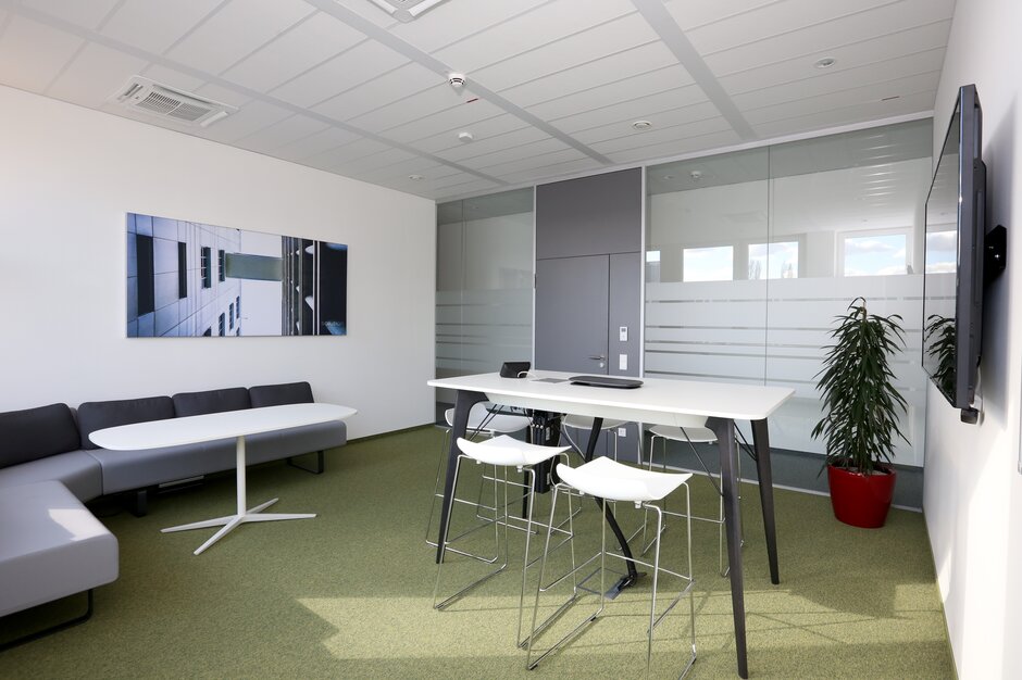 Room with high table and white barstools. 