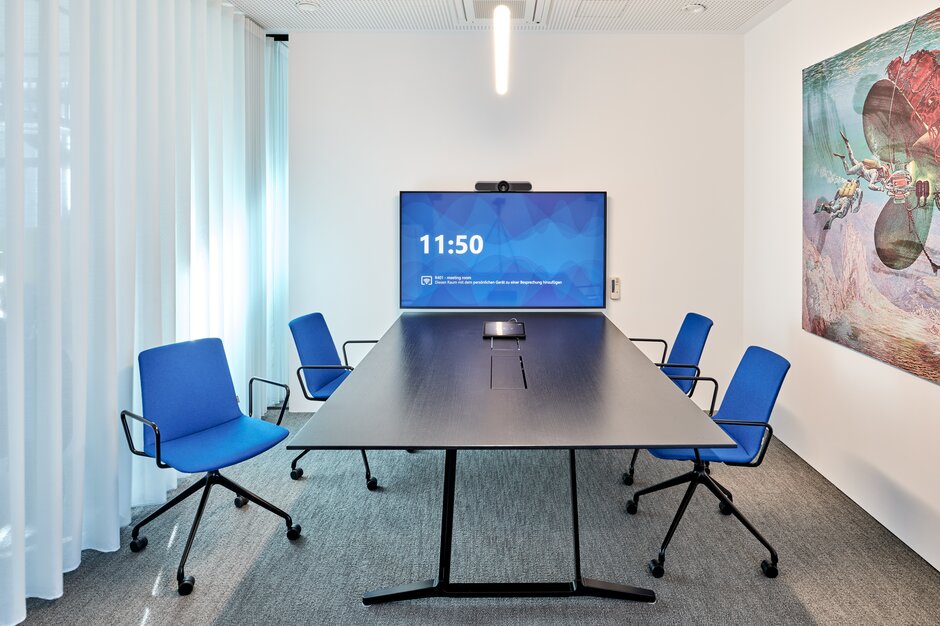 Blaue pulse Konferenzstühle mit Konferenztisch und Bildschirm. | © raumpixel.at