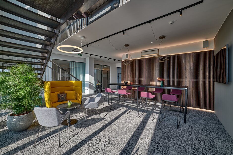 Black high table with purple barstools next to a yellow lounge seating with gray conference chairs. | © raumpixel.at