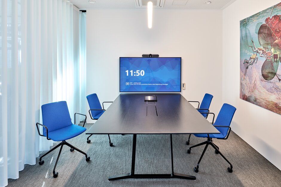 Meeting room with blue conference chairs and a dark table. | © raumpixel.at