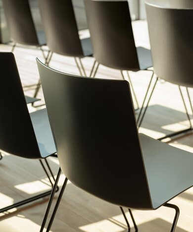 Rangées de chaises noires dans une pièce avec un plancher en bois, vue détaillée