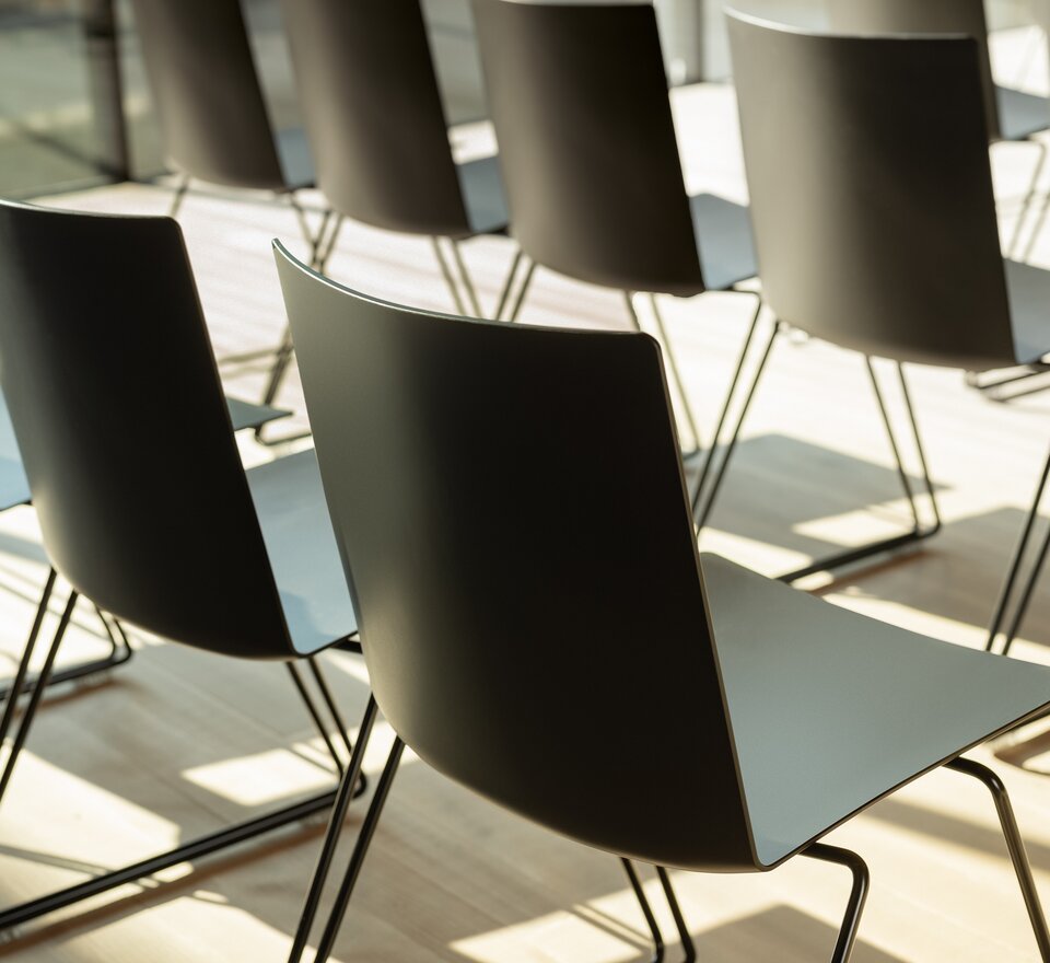 Rangées de chaises noires dans une pièce avec un plancher en bois, vue détaillée