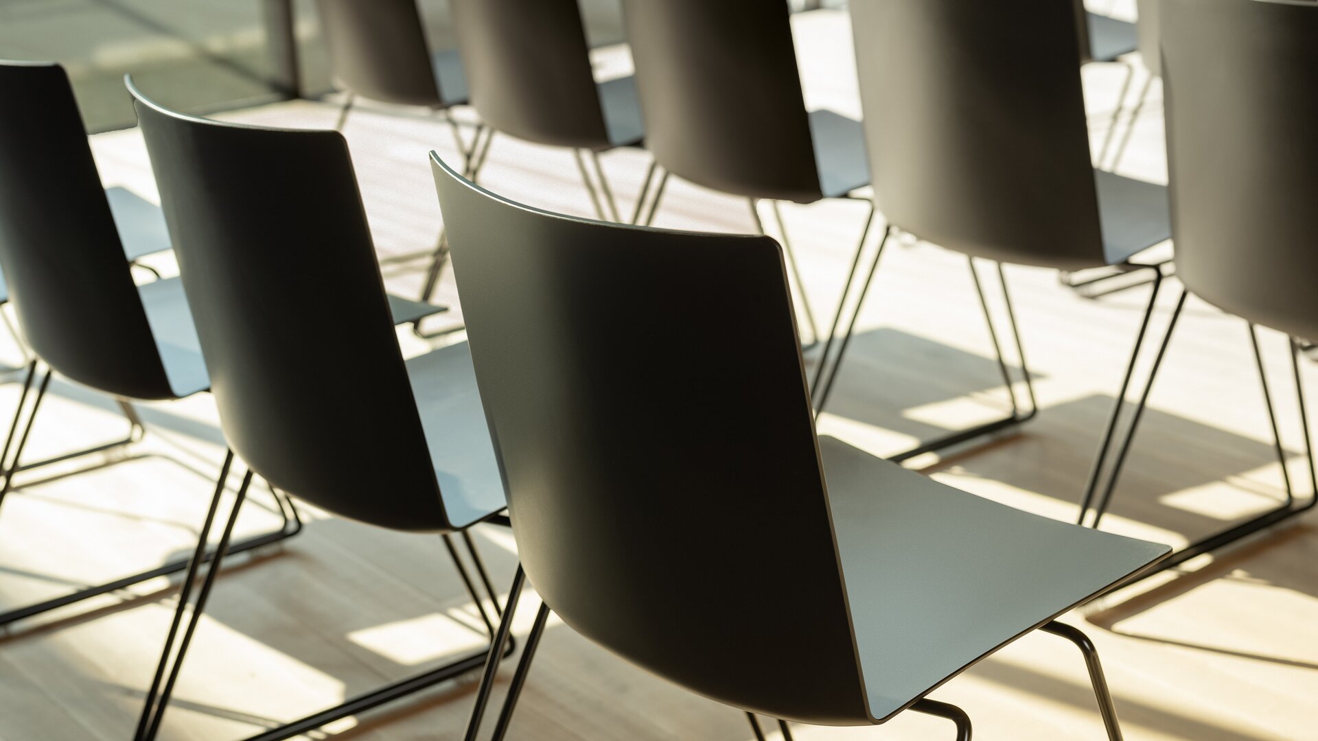 Rangées de chaises noires dans une pièce avec un plancher en bois, vue détaillée