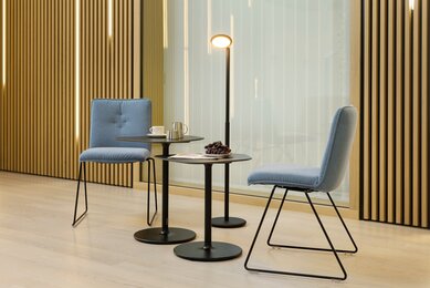 Two blue padded skid-base chairs in front of a wooden wall.
