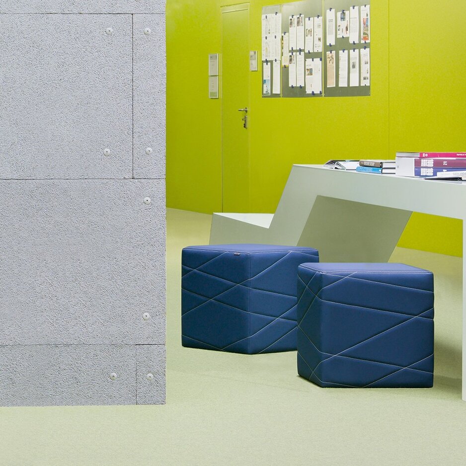 Two blue seating cubes in an office with a green wall.