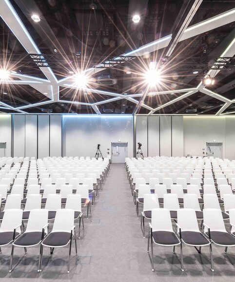Big hall with white row chairs.