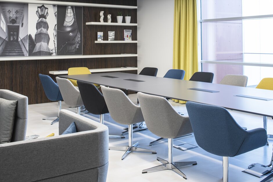 Salle de conférence avec chaises de conférence multicolores et meubles rembourrés.