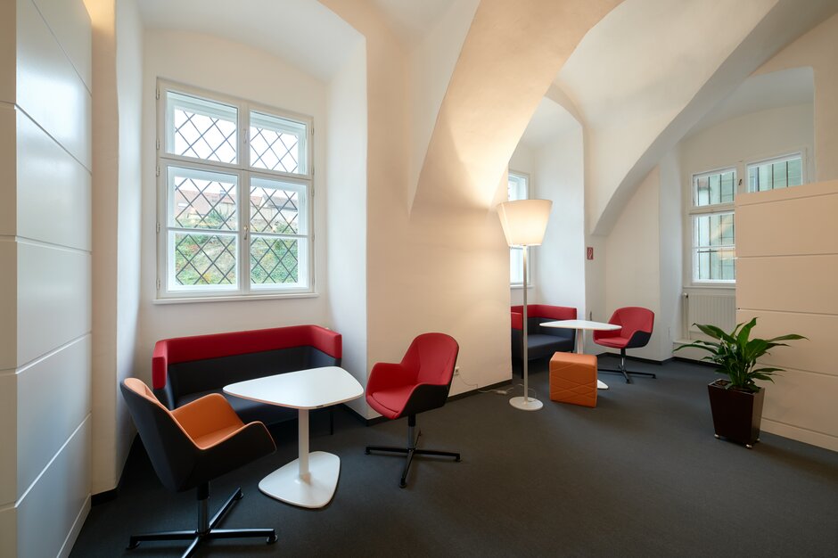 FH IMC | © raumpixel.at Fensternischen mit rot-orangen Möbeln und weißen Bistrotischen. | © raumpixel.at
