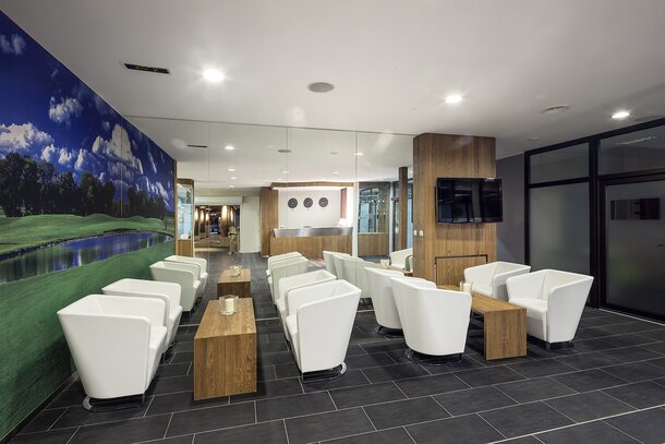 Bar with white armchairs and wooden tables.