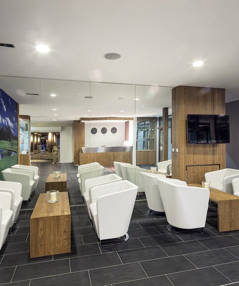 Bar with white armchairs and wooden tables.