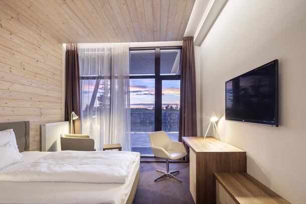 Hotelkamer met groot raam en witte stoel