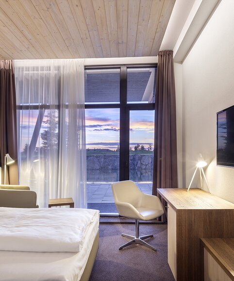Hotelkamer met groot raam en witte stoel