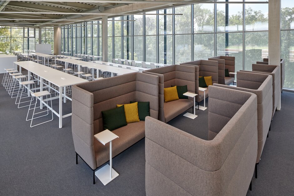 JKU Learning Center | © raumpixel.at Brown lounge seating in front of white high tables with white barstools. | © raumpixel.at