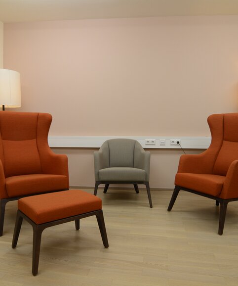 Two orange wing chairs on a wooden floor.