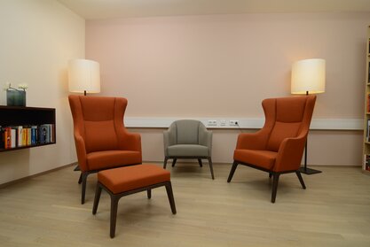 Two orange wing chairs on a wooden floor.