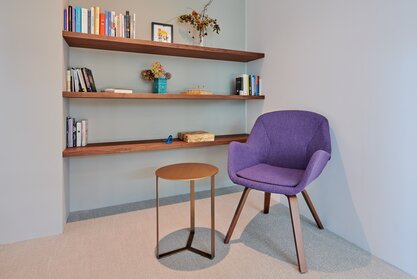 Purple conference chair in front of a wooden bookshelf. | © raumpixel.at