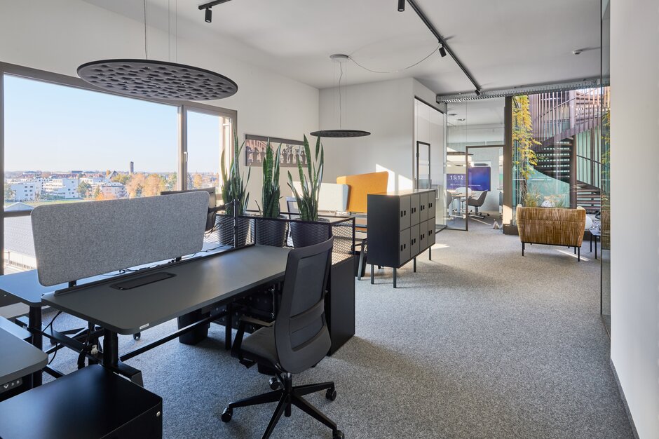 Dark desk with a dark swivel chair in an office. | © raumpixel.at