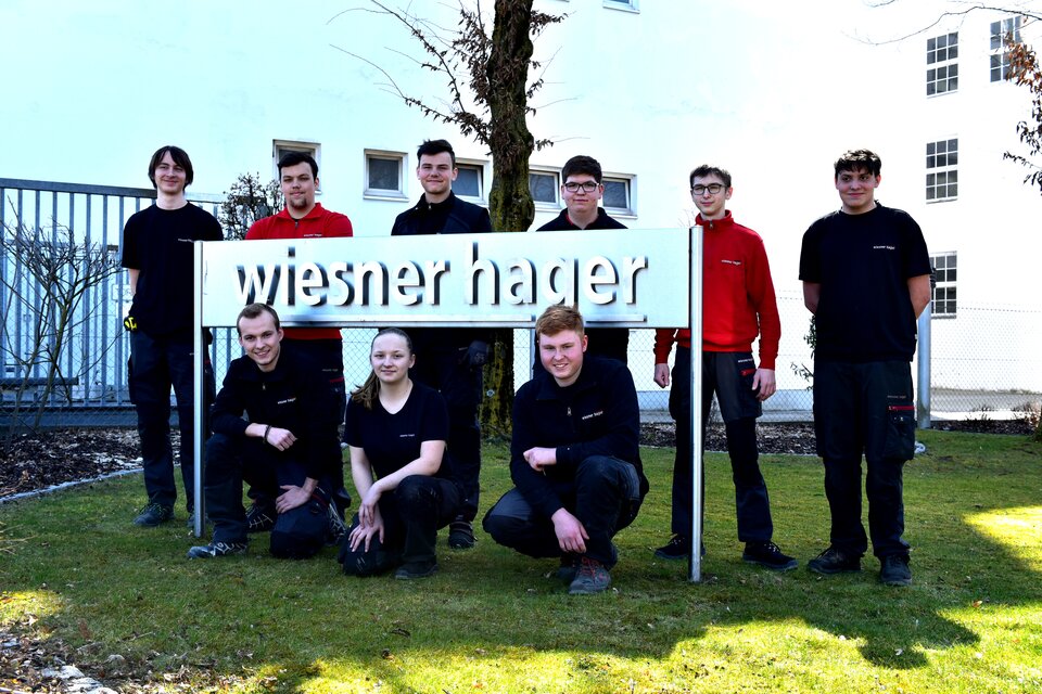 Gruppenfoto von Lehrlingen vor dem Wiesner-Hage Logo