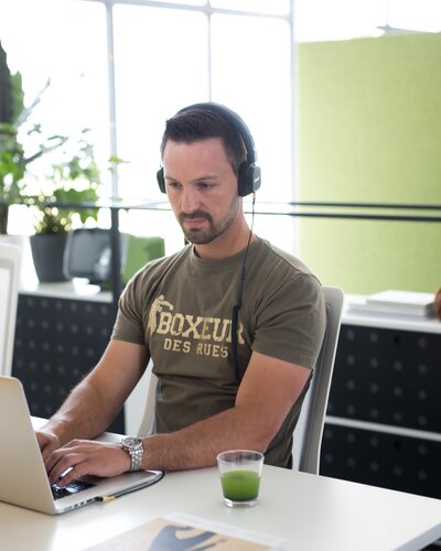 Person works with headphones on laptop.