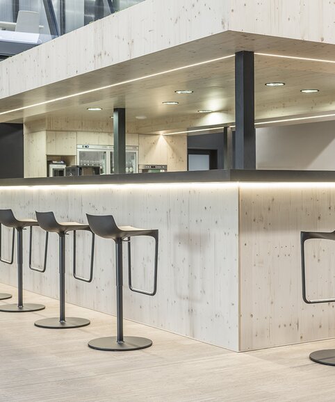 Zwarte barkrukken aan een bar die gemaakt is van lichtgekleurd hout