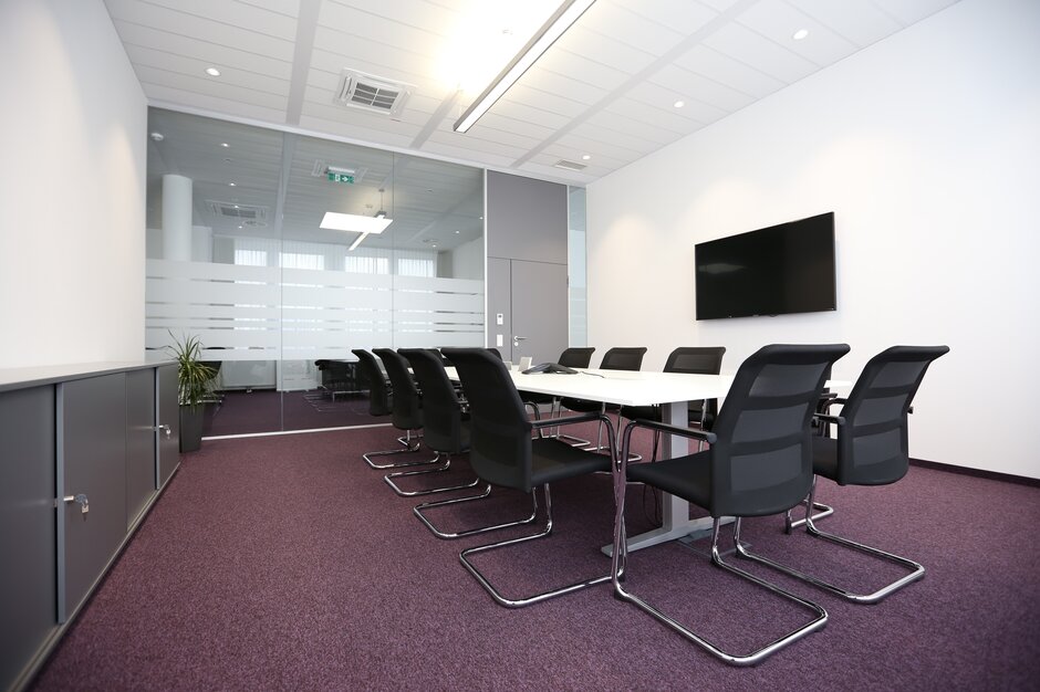 Salle de conférence avec fauteuils de luge foncés et plancher rouge.