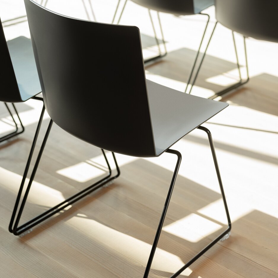 zwarte stoel met draadslede onderstel op een houten vloer
