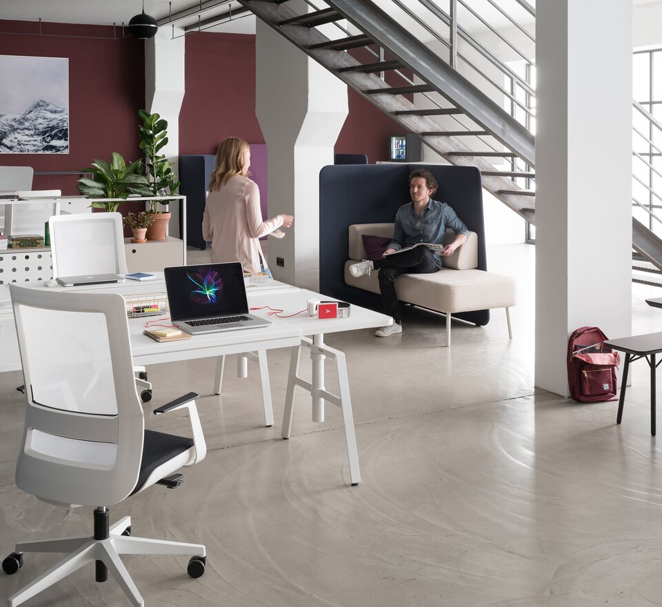 Zwei Personen in großem hellen Büro mit etio Schreibtisch. 