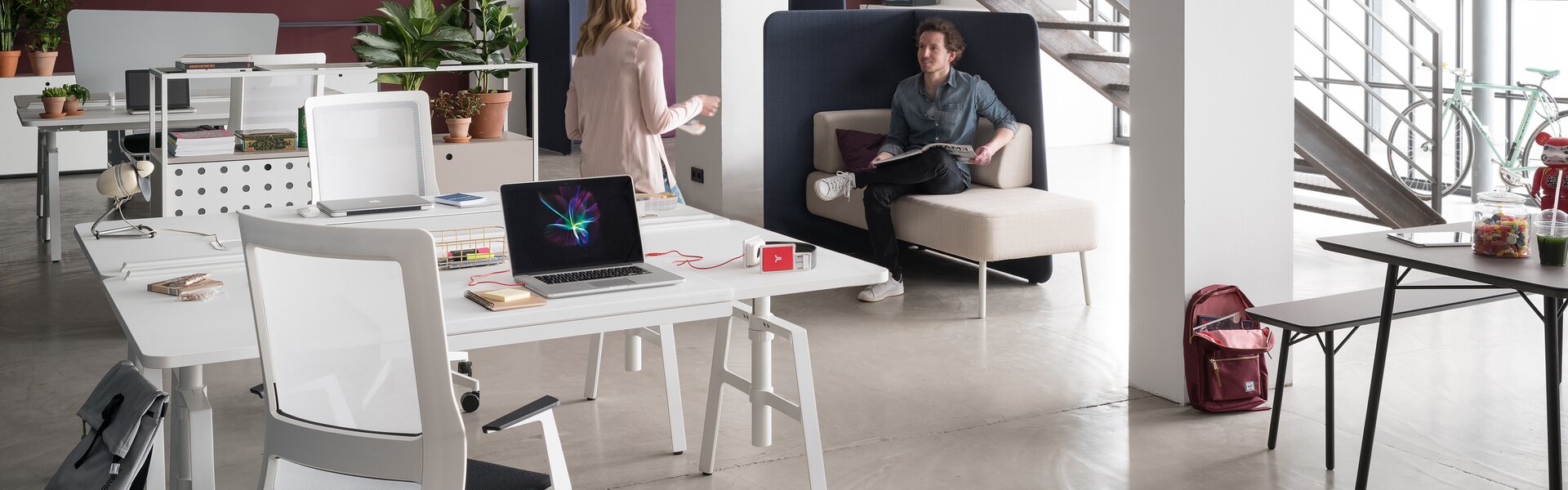 Zwei Personen in großem hellen Büro mit etio Schreibtisch. 