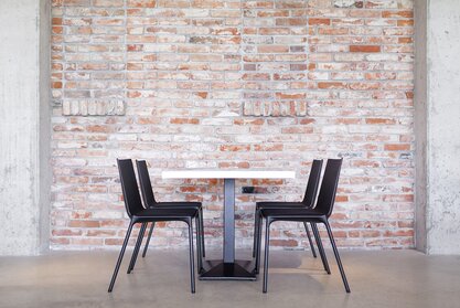 Zijaanzicht van een tafel met wit blad en zwarte stoelen