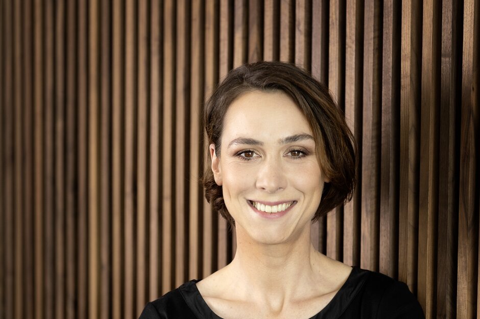 Porträt Laura Wiesner Laura Wiesner steht vor einer Holzwand.